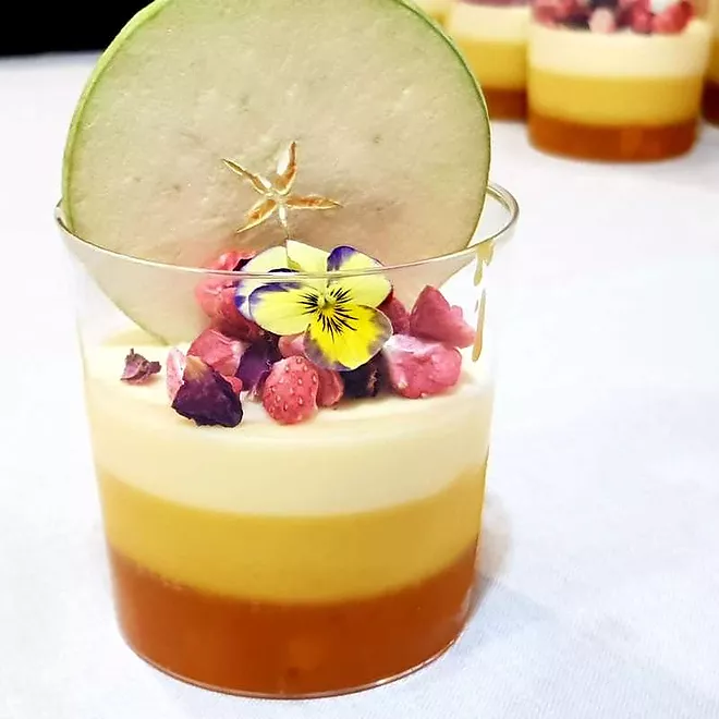 Passion fruit mousse, creamy mango and vine peach compote with lyophilized strawberry garnish, rose petals, though flowers and lyophilized green apple